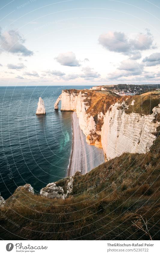 Coast with rocks and sea in sunset Pebble beach France Normandie Étretat Moody evening mood Clouds Ocean Rock cliffs Landscape Nature coast Exterior shot