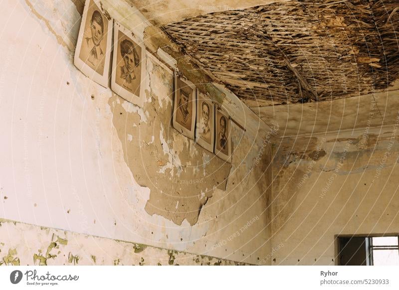 Six Black And White Paper Portraits Of Young Pioneers, Heroes Of WW2 War On Cracked Peeling Wall In Classroom Of Abandoned School After Chernobyl Nuclear Disaster In Evacuation Zone.