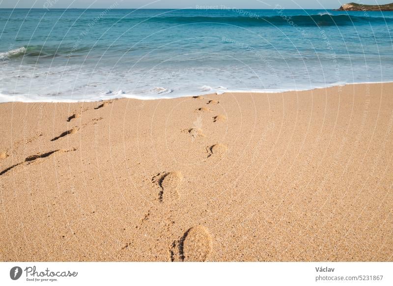 Footprints in the sand from a man sinking into the deep Atlantic Ocean on the sandy beach of Praia da Ilha do Pessegueiro near Porto Covo, western Portugal