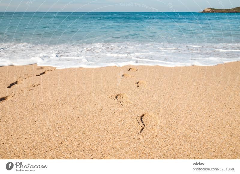 Footprints in the sand from a man sinking into the deep Atlantic Ocean on the sandy beach of Praia da Ilha do Pessegueiro near Porto Covo, western Portugal