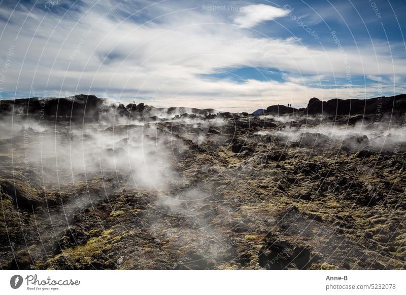 Hiking on a young lava field of Krafla volcano in northern Iceland, with steaming fissures on a nice cool sunny day. In the background people as sillhouettes .