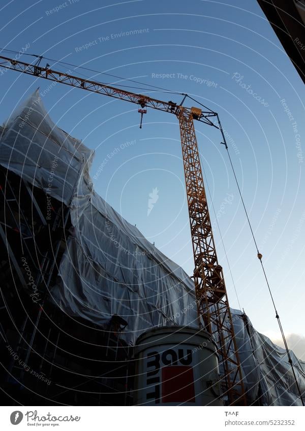 Construction site with crane and scaffolding covered with protective film in the city center for closing time Crane Construction crane Scaffold Scaffolding