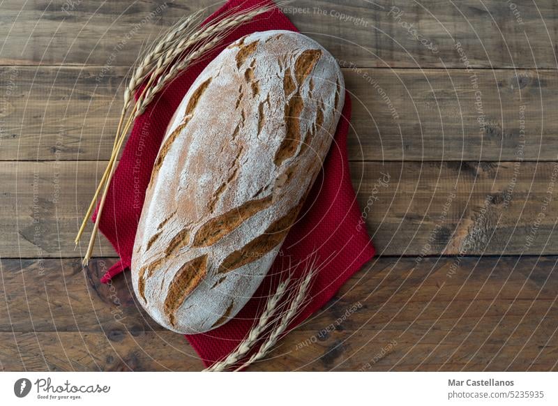 Piece of rustic bread on wooden background with ornaments of ears of wheat. Copy space. Bread food piece cereal ears of corn boards top view space copy