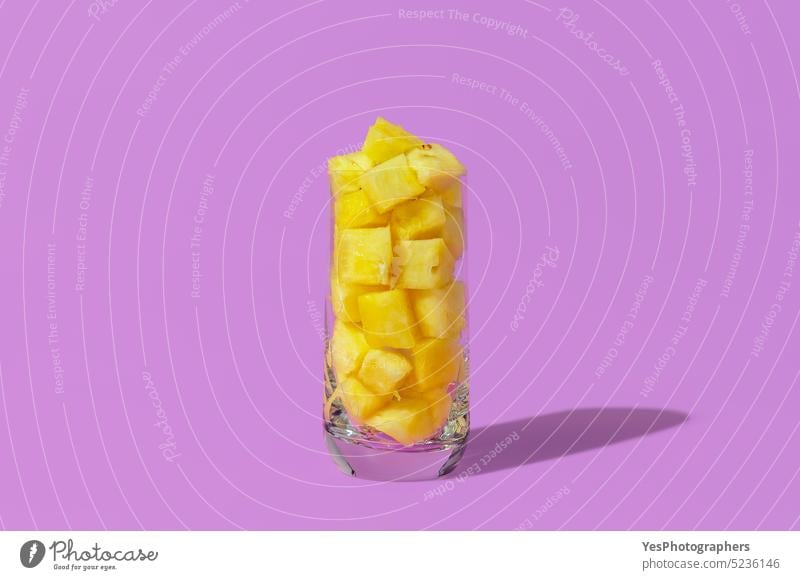 Pineapple juice concept. Glass with pineapple cubes isolated on a purple background ananas bright close-up color cuisine cut out delicious dessert diet food