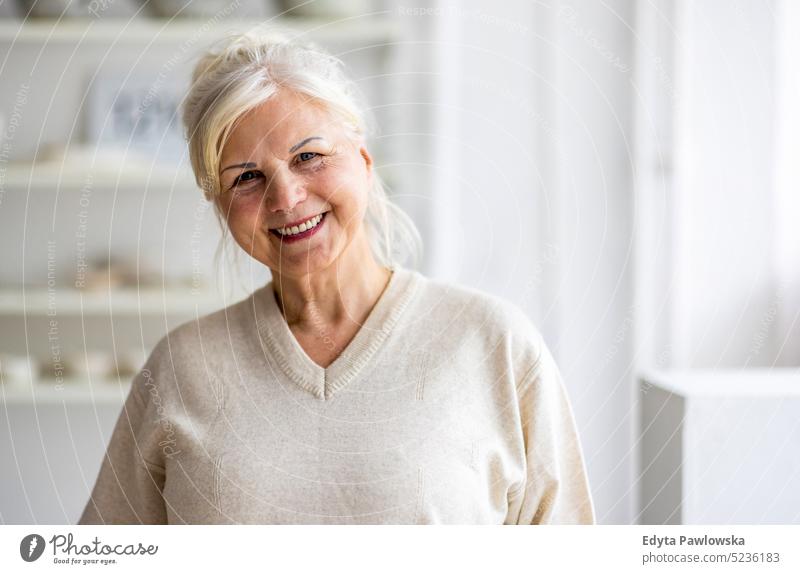 Portrait of smiling senior woman looking at camera real people indoors loft window home mature adult one person attractive successful confident beautiful female