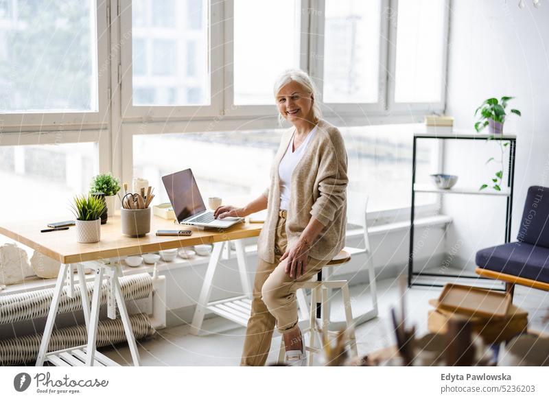 Portrait of smiling mature businesswoman working in an office real people senior indoors loft window home mature adult one person attractive successful