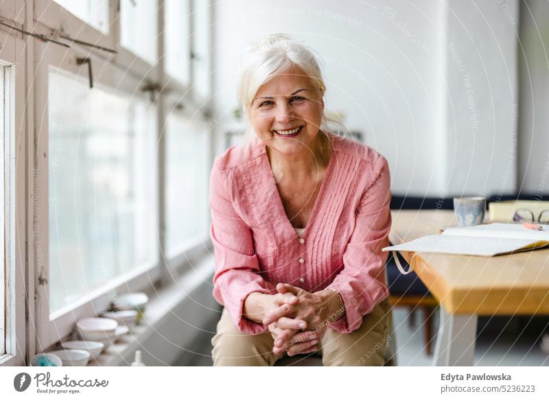 Portrait of smiling senior woman looking at camera real people indoors loft window home mature adult one person attractive successful confident beautiful female