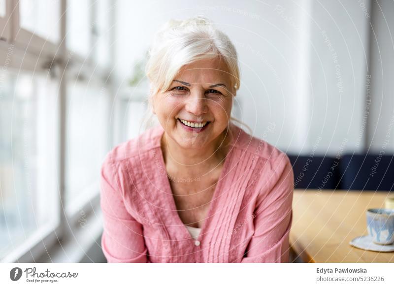 Portrait of smiling senior woman looking at camera real people indoors loft window home mature adult one person attractive successful confident beautiful female