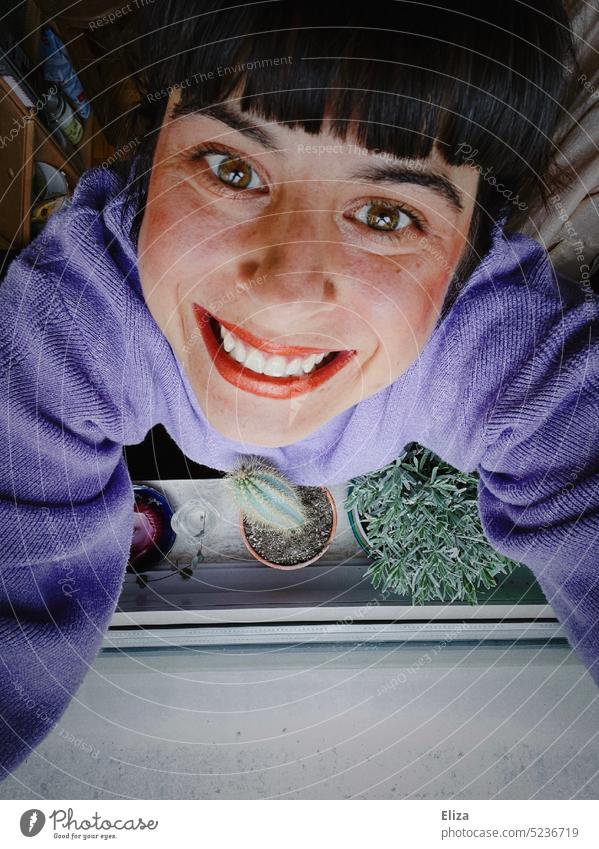 A woman stands with cactus at the window and grins euphorically into the camera Woman Grinning Window Euphoric Cactus surreal Excessive purple Window board