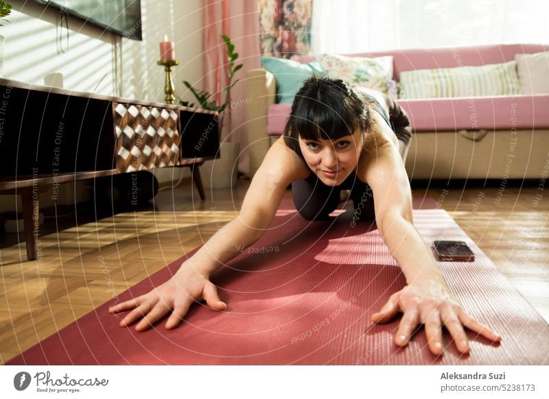 Beautiful woman practicing yoga at home. Stylish cozy home interior. Doing yoga exercises and enjoying early morning. Close-up portrait of funny angle. Healthy lifestyle