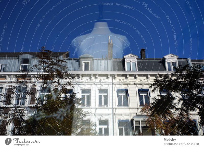 Shop window with white dress for wedding and reflecting white facade against blue sky in sunshine in Station Straat in Maastricht on the Meuse River in the province of Limburg of the Netherlands