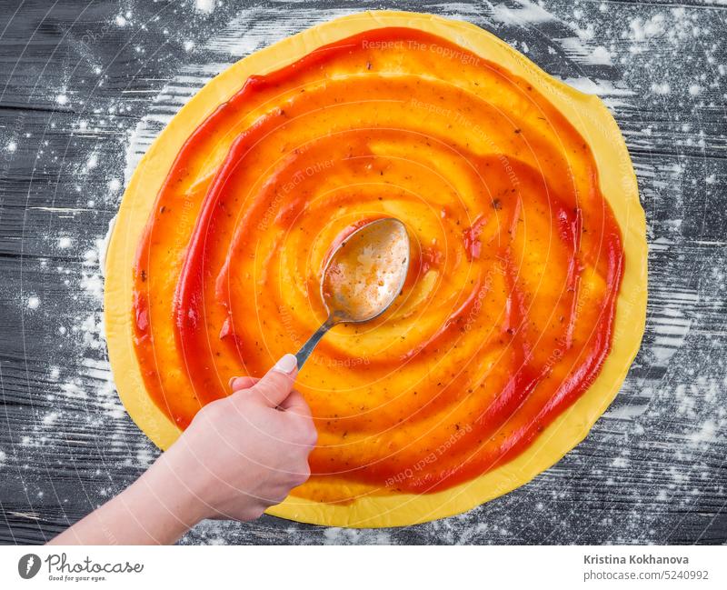 Female hand adding red sauce. Italian pizza preparation on blue wooden table. Cooking concept. making italian process chef baking blank catchup colorful cooking