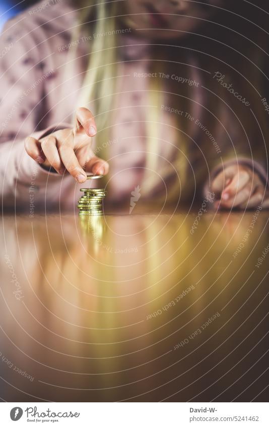 Child stacks a few coins - dealing with money at a young age Money child benefit Coins Parenting Costs investment Save assets Hand Girl Pocket money