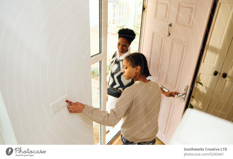 Teen girl turning off lightswitch and leaving house teen leave saving energy electricity home family multiracial hallway togetherness lifestyle responsibility