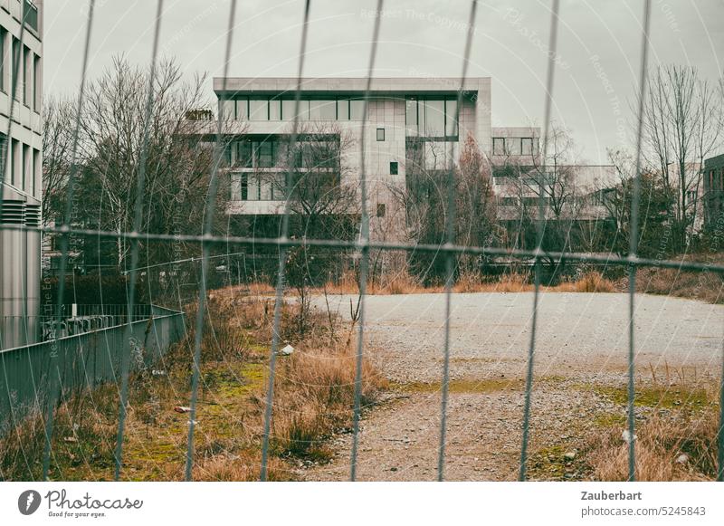 Villa in modern architecture, glass and concrete, functional behind the lattice of a construction fence, in front of it wasteland Modern Architecture Bauhaus