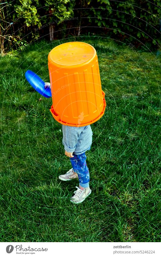 Child with bucket on head and frisbee in hand Disorientated Orientation Blind Search Headwear Bucket Anonymous Stand Meadow Garden game of hide-and-seek covert