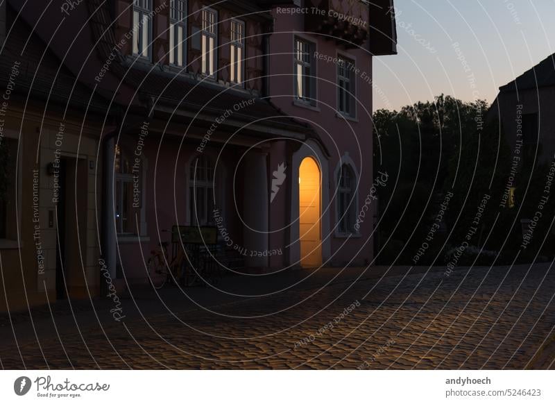 An old house with lighted entrance and cobblestone street in a small town in Germany aged ancient antique arch architecture blue brick buckow building city