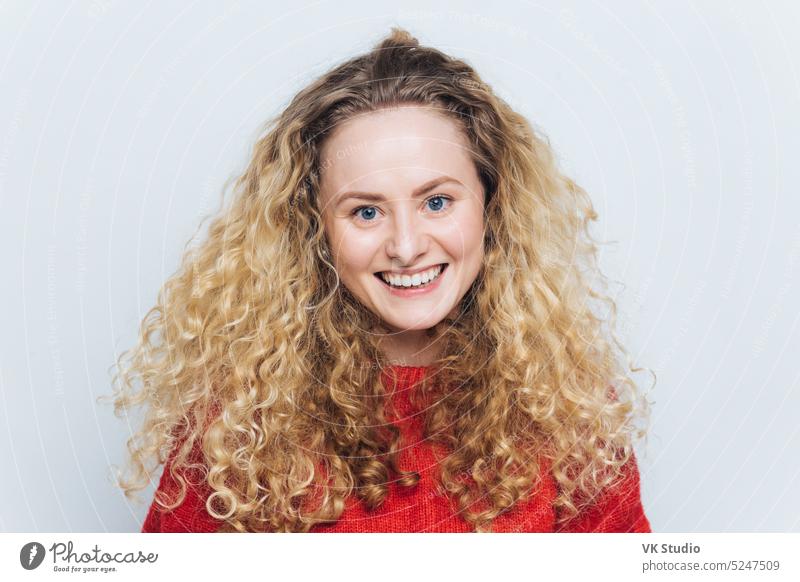 Happy smiling woman with curly luxurious hair, glad expression, satisfied to recieve good news from friend, isolated over white background. People, facial expressions and positive emotions concept.