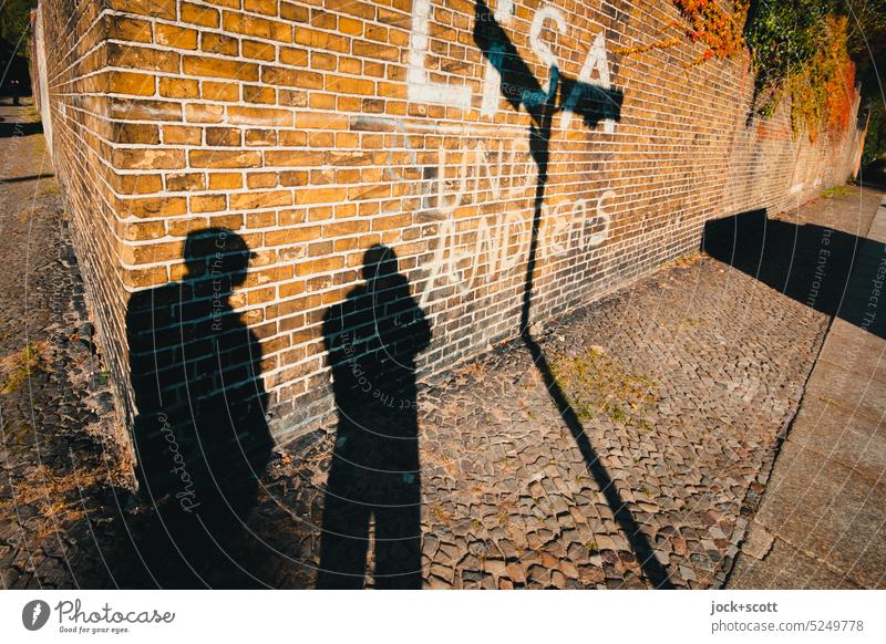 Lisa and Andreas stand at the old cemetery wall Wall (barrier) Street art Kreuzberg Berlin Creativity Spray Word Sunlight Contrast Silhouette Shadow play Warmth