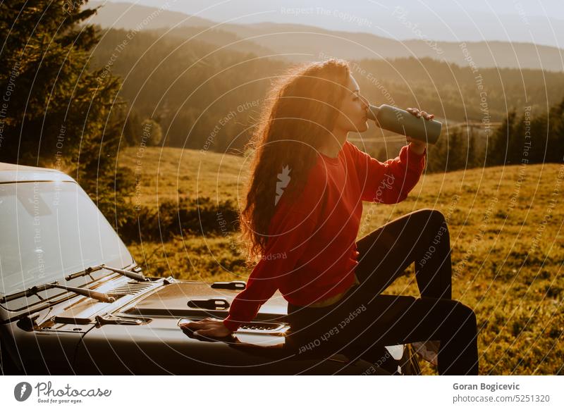 Young woman relaxing on a terrain vehicle hood at countryside auto young caucasian holiday summer trip car vacation female lifestyle outdoors person adult