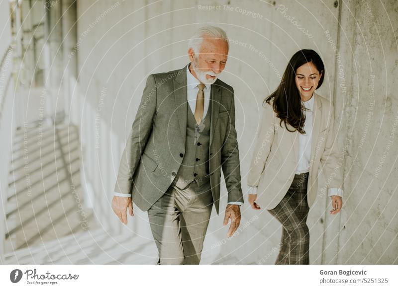 Senior corporate business professional and his young female colleague climbing at stairs in office corridor adult businessman businesspeople businesswoman busy