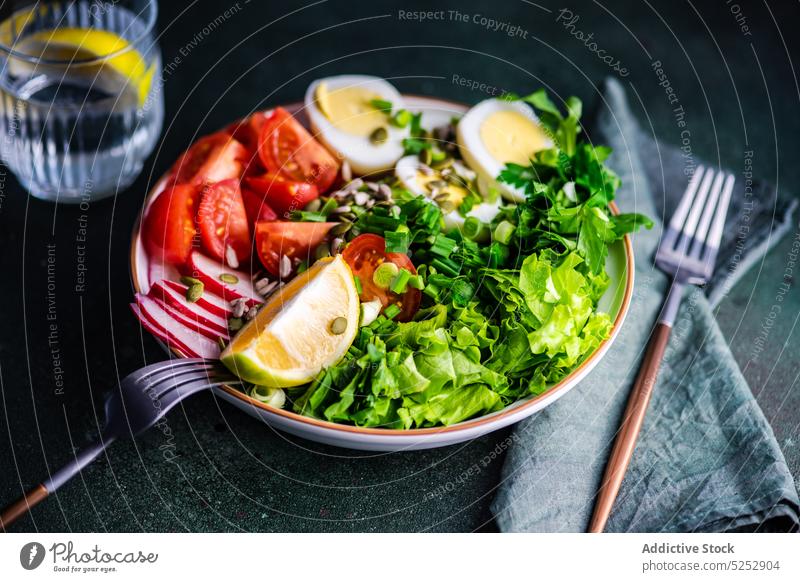 Healthy raw vegetable salad boiled concrete cutlery dinner egg food fresh glass healthy herb lemon lettuce napkin organic radish rocket seed bowl served tomato