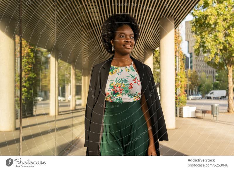 Stylish ethnic female standing near building woman pensive dreamy thoughtful urban style city sun african american street calm young contemplate jacket casual