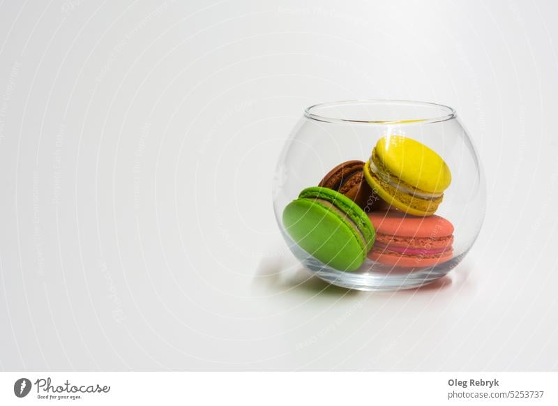 Multicolored macaroons in a glass kitchen jar dessert food cookie bakery cake pink pastry sweet traditional french biscuit yellow background closeup