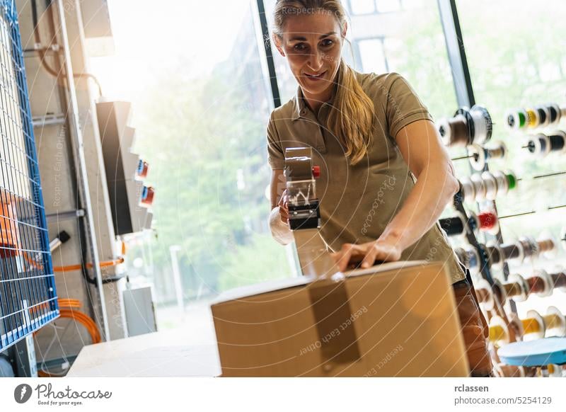 female worker sealing or taping packing case with adhesive tape, using dispenser, at warehouse of freight forwarding company box tape adhesive delivery post