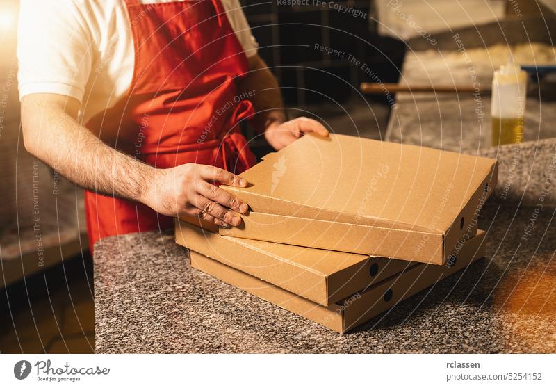 pizza baker packing pizzas in a box for delivery at italian pizzeria fold tasty cheesy man salami delivery service smile happy hat wood fire brick oven