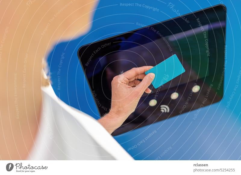 Woman pays for charging on a  Hypercharger or Supercharger with Nfc or Rfid card for electrical or hybrid automobiles, with copyspace for your individual text. Charge electromobility concept image.