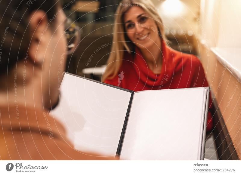 close up of couple with blank menu card choosing dishes at restaurant, with copyspace for your individual text. date elegant smiling looking two dating