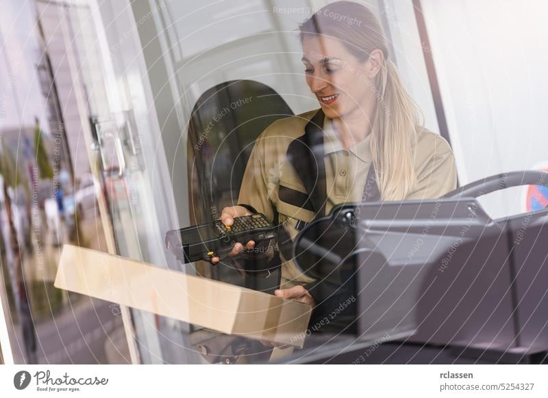 Female delivery driver using barcode scanner checking pacel in a van in the city holding laser scanner computer touchscreen touching storage equipment