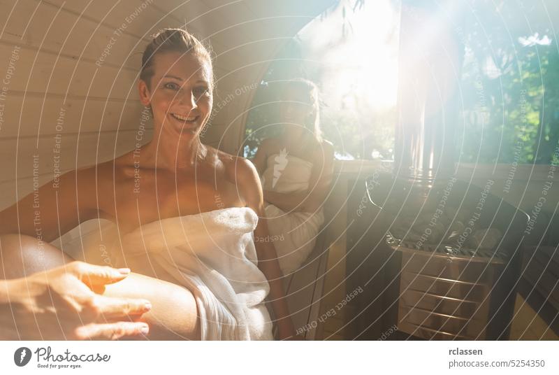 Relaxed woman at the wooden barrel sauna at Summer in norway. People are relaxed and enjoy the holiday while relaxing in the finnish sauna cabin. friends