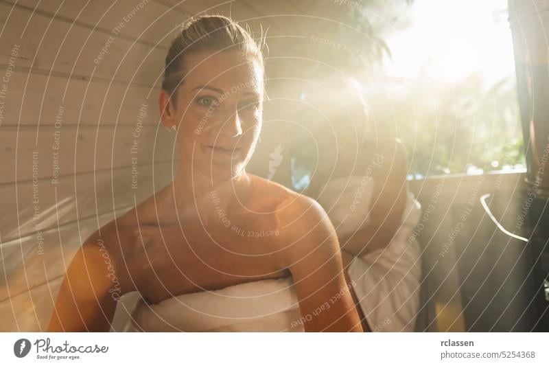 Happy girlfriends relaxing at the wooden barrel sauna at Summer in norway. People are relaxed and enjoy the holiday while relaxing in the finnish sauna cabin.