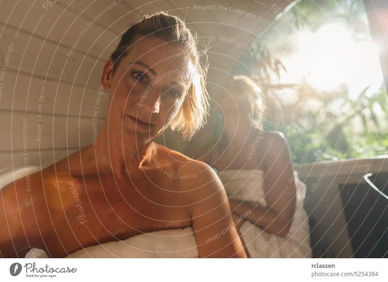 Relaxed woman at the wooden barrel sauna at Summer in norway. People are relaxed and enjoy the holiday while relaxing in the finnish sauna cabin. friends