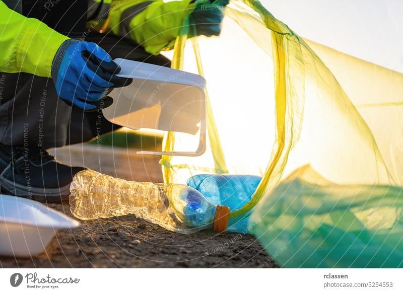 Volunteer man collecting plastic rubbish in park at sunset. Cleaning environment concept garbage activist bin bottle clean conservation dump container