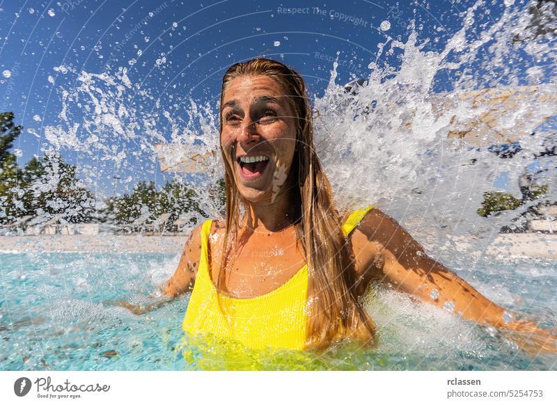 Happy woman enjoying hydrotherapy and splashing water stream of a waterfall in spa pool smiling attractive refreshing tub shoulder vacation wellness jet thermal