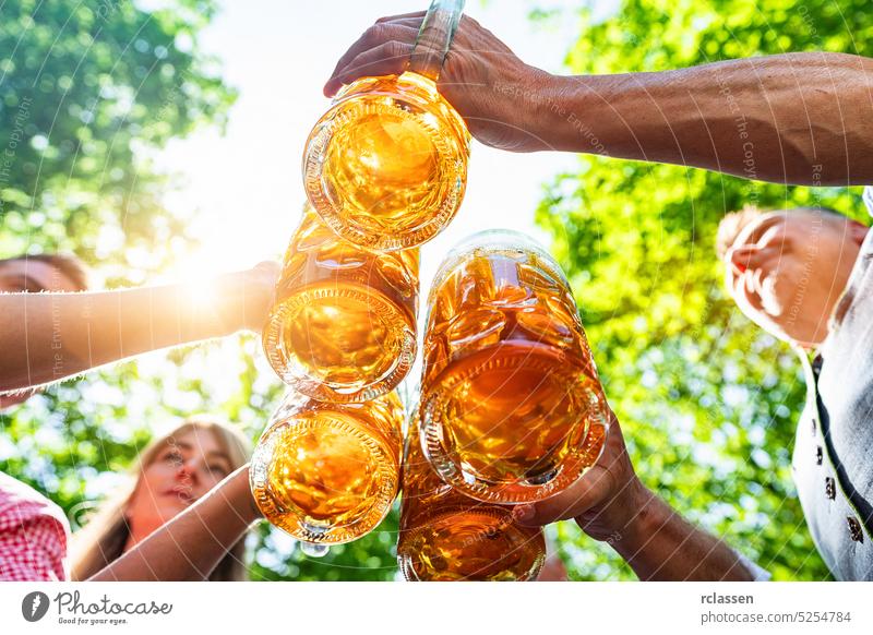 Group of happy Bavarian friends drinking and toasting beer at Oktoberfest, folk or beer festival in germany tap hands brezen bavarian lederhosen munich alcohol