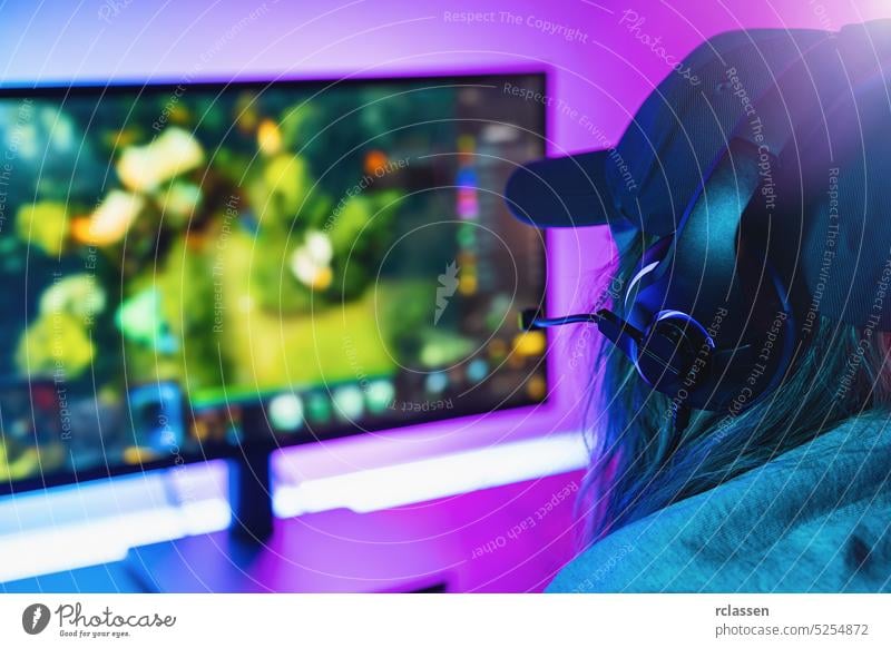 female Gamer plays strategy Online Video Game on her Personal Computer. Room Lit by Neon Lights in Retro Arcade Style. Online Cyber e-Sport Internet Championship.