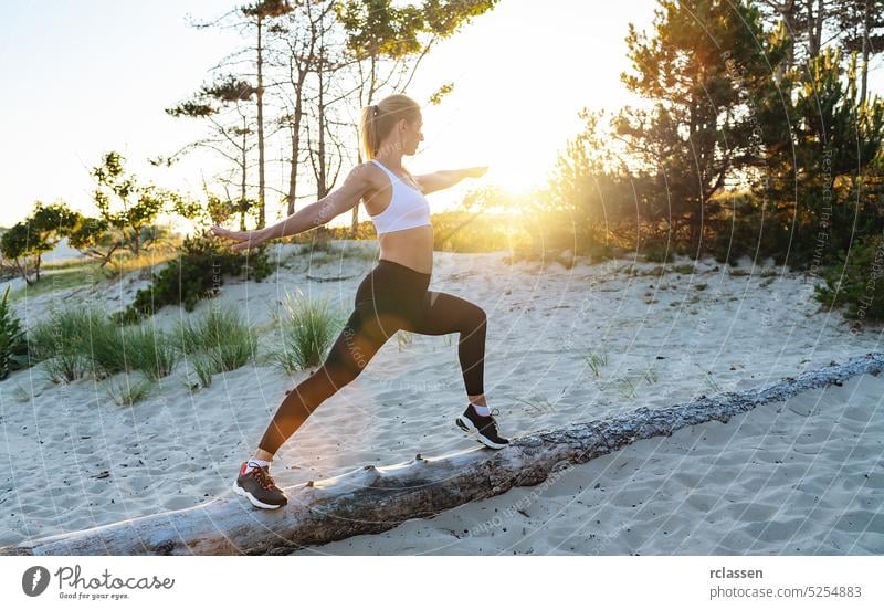 Young woman practicing yoga on a Tree trunk at beach in the morning sunset sunrise jogging athlete fit exercise workout joga chi warrior female pose peace