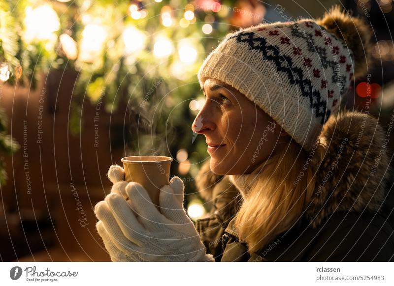 Woman in front of Christmas tree on winter market drinking hot wine christmas woman girl lifestyle holiday lights fun young beautiful season decoration emotion