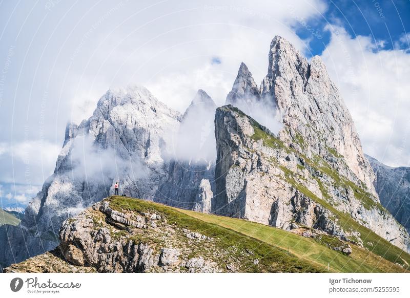 A man raising his hands in front of epic Furchetta and Sass Rigais peaks in Seceda, Dolomites Alps, Odle mountain range, South Tyrol, Italy, Europe. Travel vacation concept