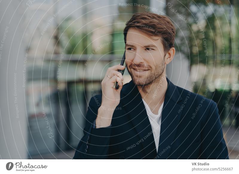 Handsome unshaven male executive worker left business building talks via smartphone man technology businessman mobile outdoors communication cellphone outside