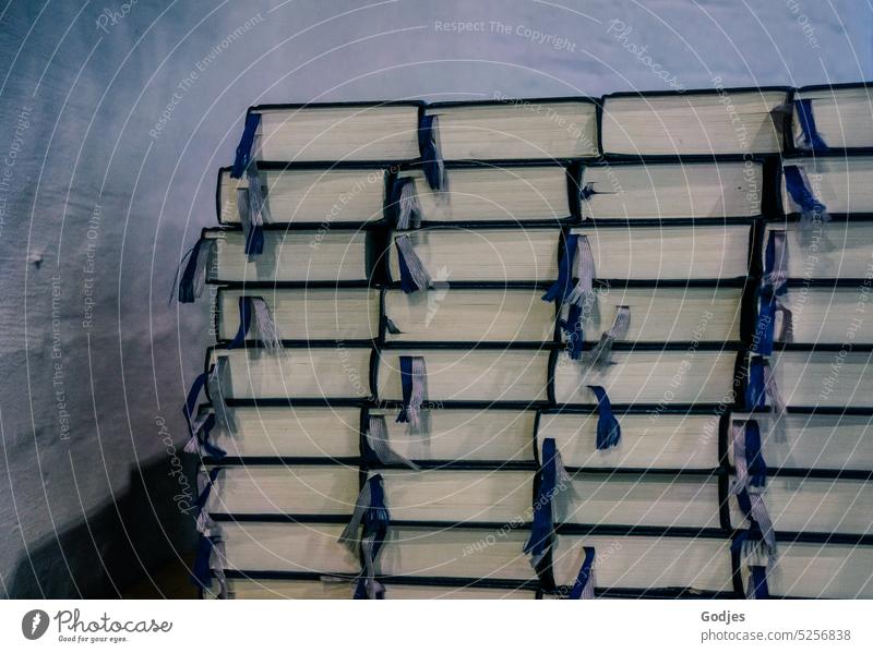 Stack of books with ribbon in front of white wall in a church pile of books Hymnals Church Church service Belief Religion and faith Christianity religion Prayer