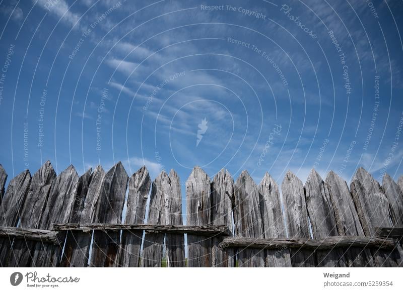 Perspective towards bright blue sky with old wooden picket fence with pointed fence ends in foreground Fence lattice fence wooden slats Border Nature Sky