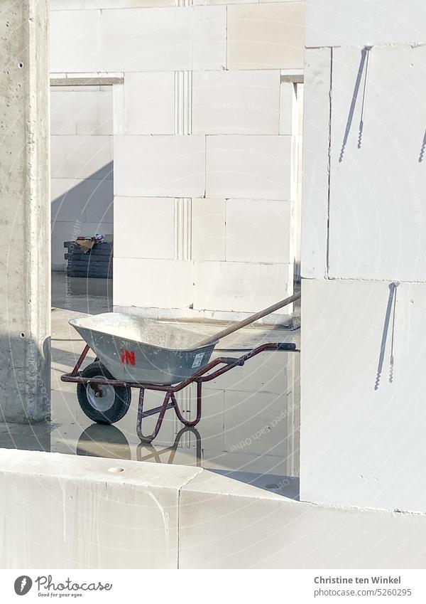 Wheelbarrow with reflection on a construction site after the rain Puddle Reflection in the water Construction site unfinished sunshine Light and shadow Sunlight