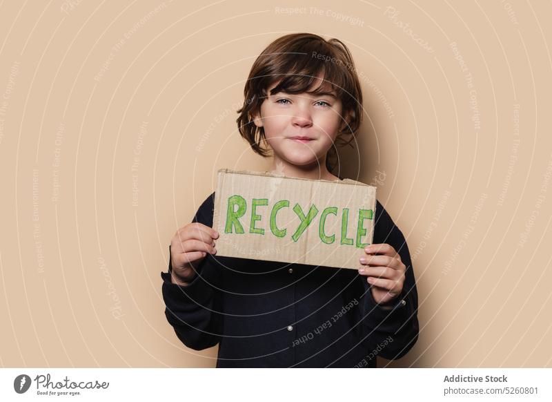 Girl showing Recycle placard at camera girl recycle protest activist environment ecology response carton kid outerwear coat problem save child reduce protect