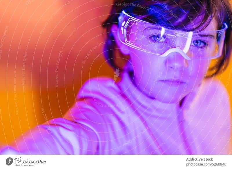 Girl in glowing futuristic glasses girl neon illuminate ornament cyberpunk portrait color bright kid dark hair goggles individuality jacket vivid modern child