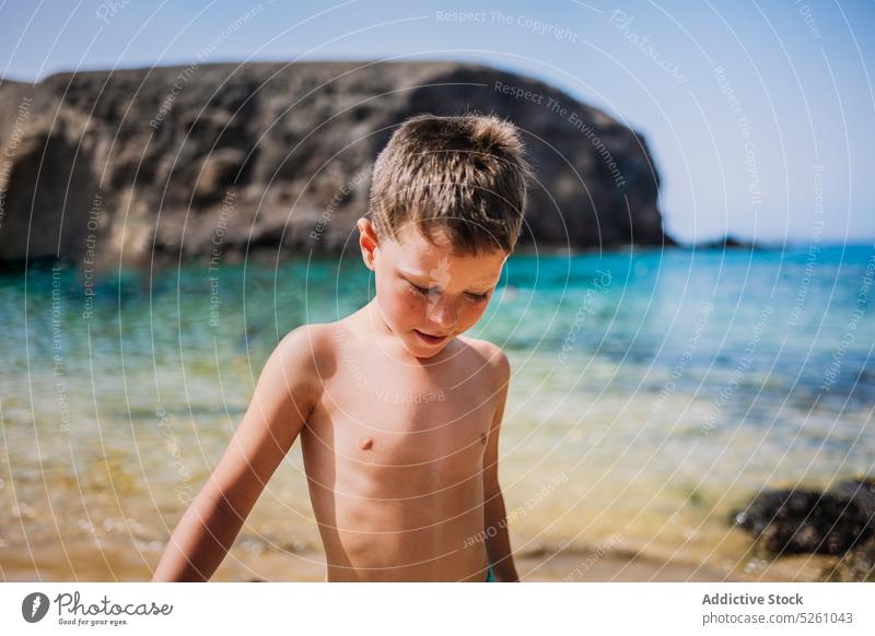 Boy in swim trunks standing on beach child boy sea water shore nature cloudless summer holiday resort kid lanzarote parrot beach spain europe vacation daylight